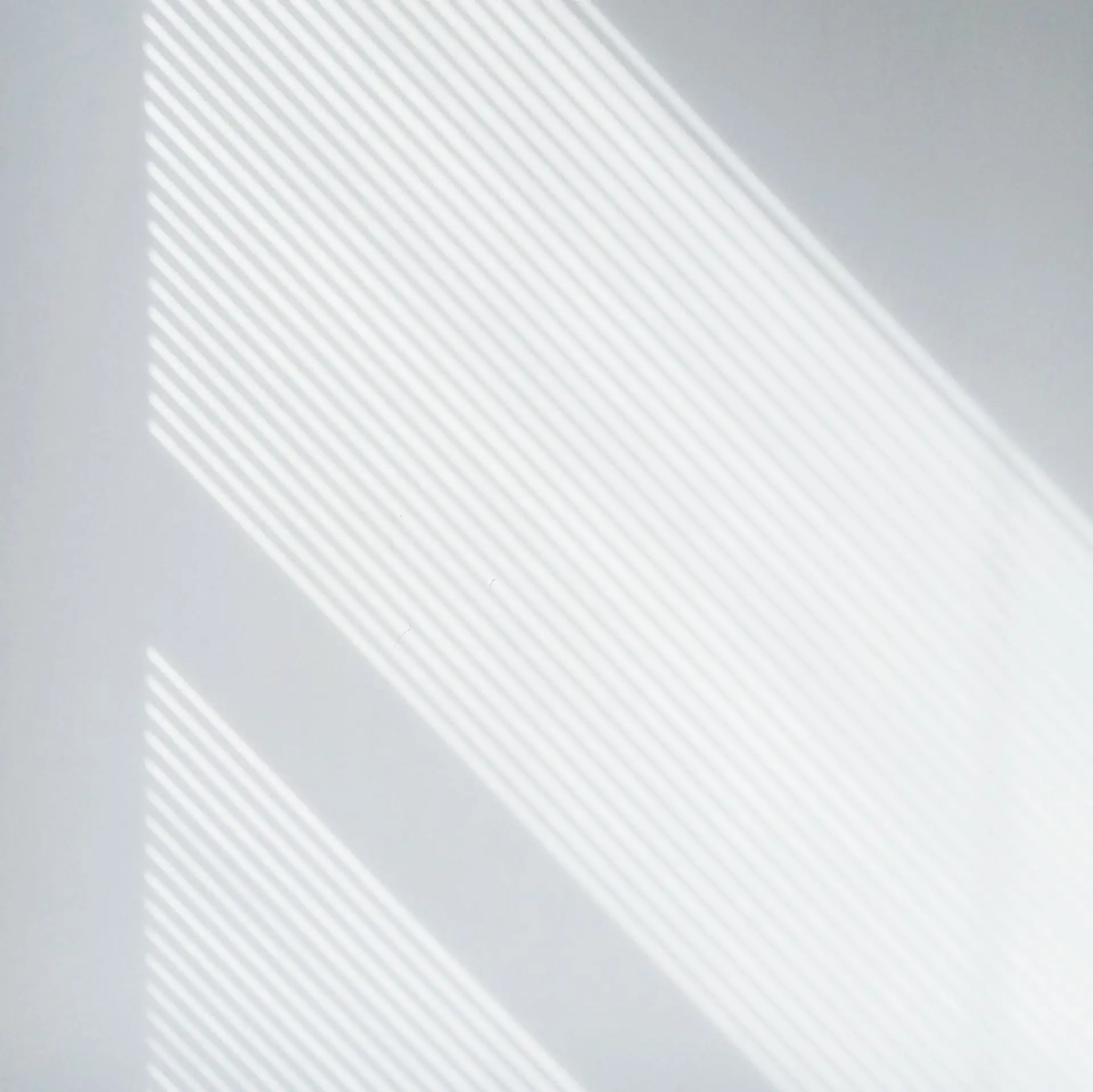 Luce del sole a strisce diagonali su una parete bianca